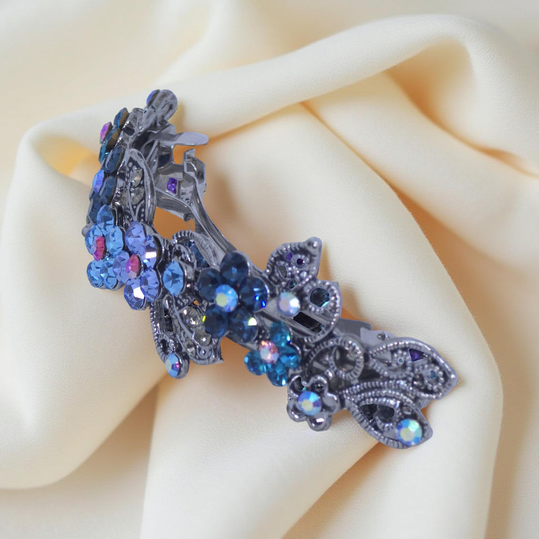 Side view of Haerime Elysia Garland Barrette in Blue – curved floral structure and antique silver leaf silhouette