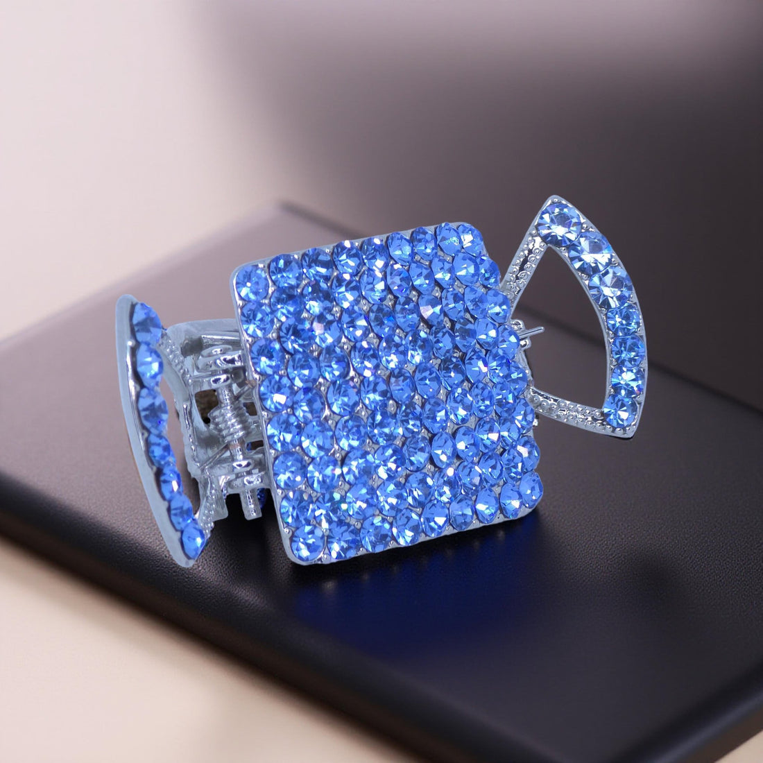 Haerime Lunette Square Claw in Blue – angled view showing mirrored claw wings and faceted crystals on cream satin background