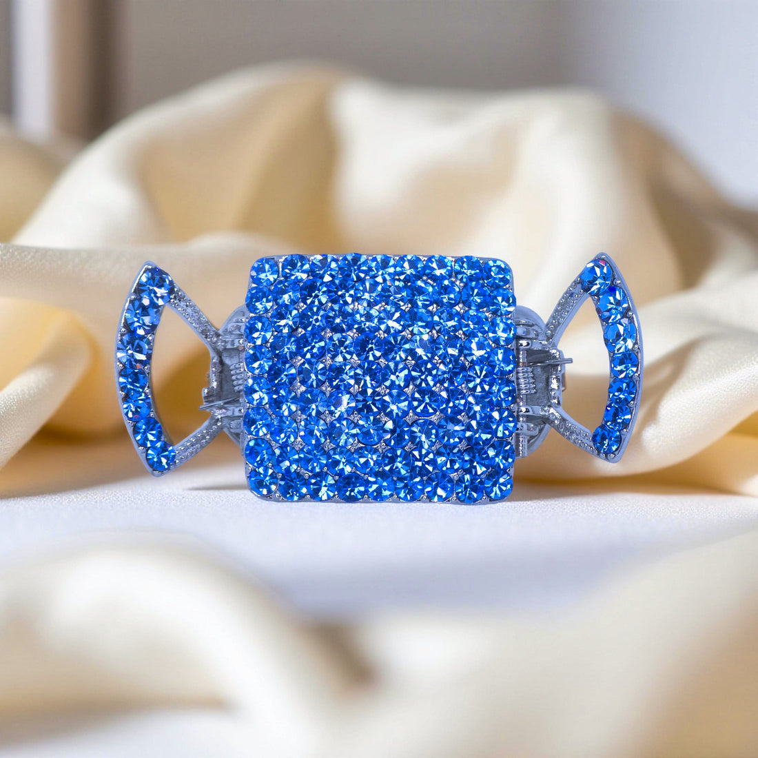 Haerime Lunette Square Claw in Blue – zoom-in of structured square crystal frame placed on cream satin pouch for bridal styling
