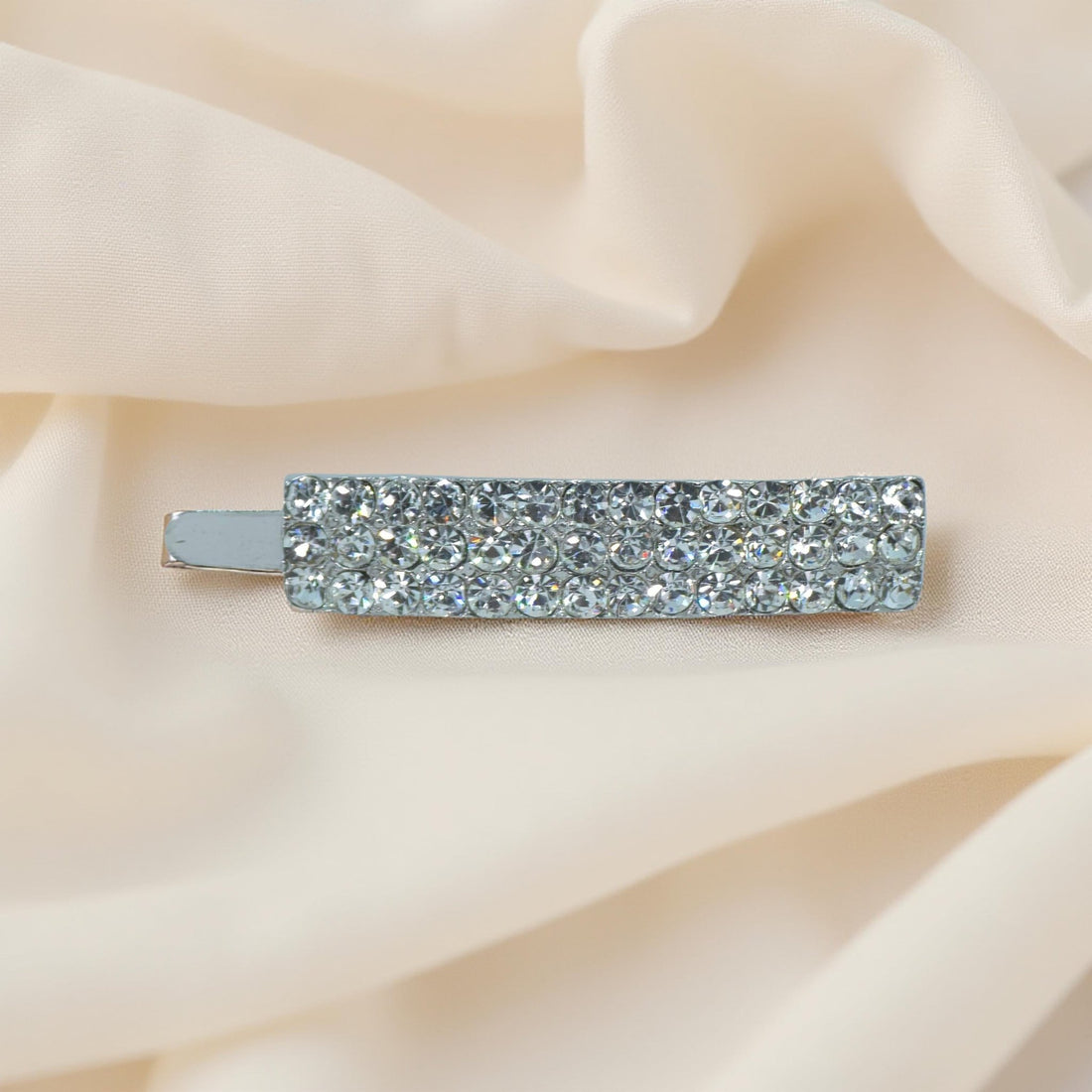 Haerime Magnetta Snap Clip in Black – top view showing sleek rectangular clip with glossy dark pavé, photographed on beige satin