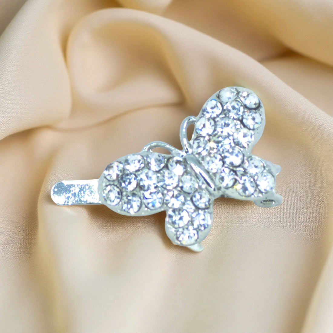 Haerime Papillon Éclat Clip in Clear – icy white crystal butterfly barrette placed on golden satin surface