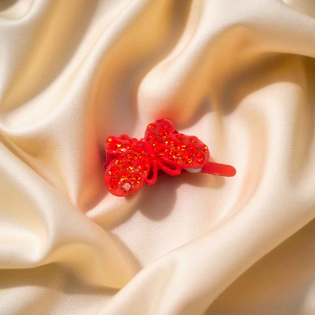 Haerime Papillon Éclat Clip in Red – close-up of ruby pavé butterfly with sculpted edges on soft satin fabric
