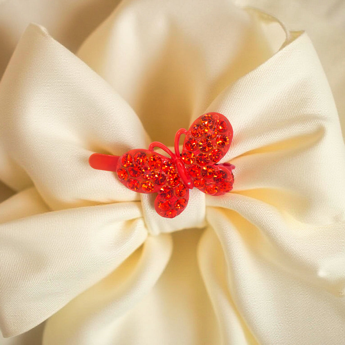 Haerime Papillon Éclat Clip in Red – bright red butterfly barrette laid flat on warm beige velvet