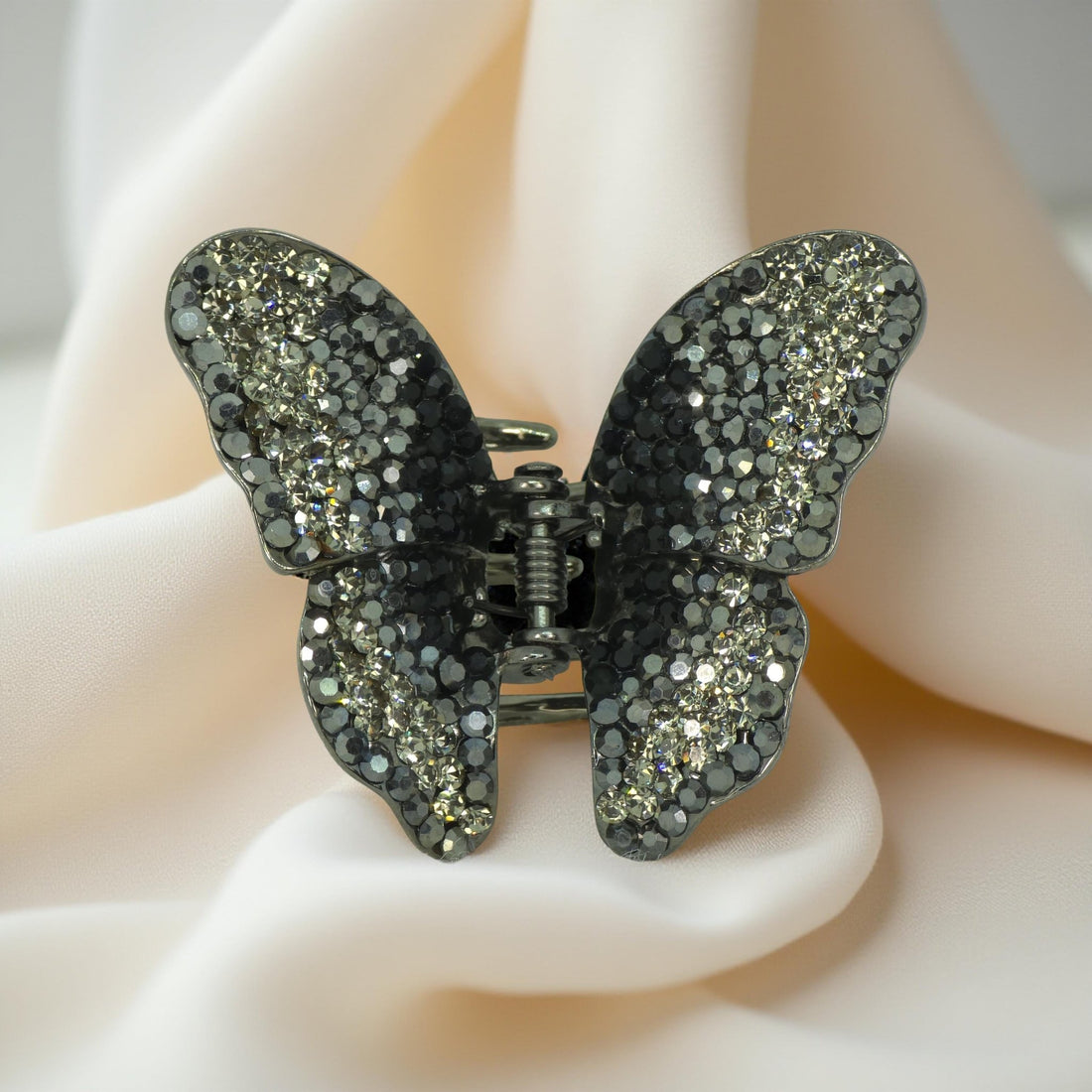 Haerime Papillora Mini Claw in Black – close-up of glossy black pavé butterfly wings resting on pastel marble surface with blurred decor