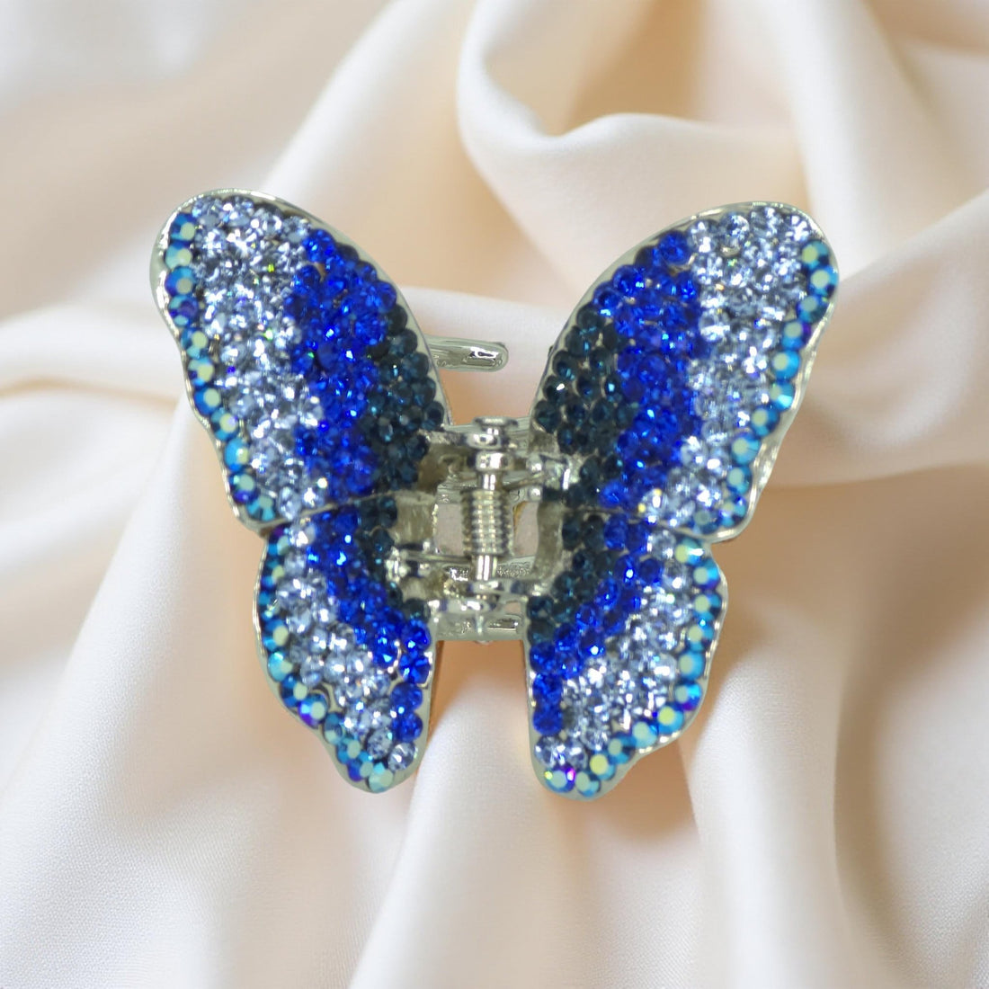 Haerime Papillora Mini Claw in Blue – top view of vivid blue crystal butterfly silhouette resting on soft ivory textile