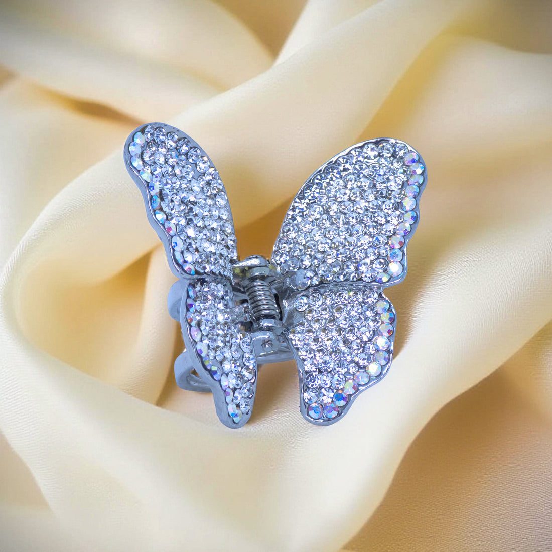 Haerime Papillora Mini Claw in Clear – close-up of icy pavé crystals and curved butterfly shape placed on ivory silke