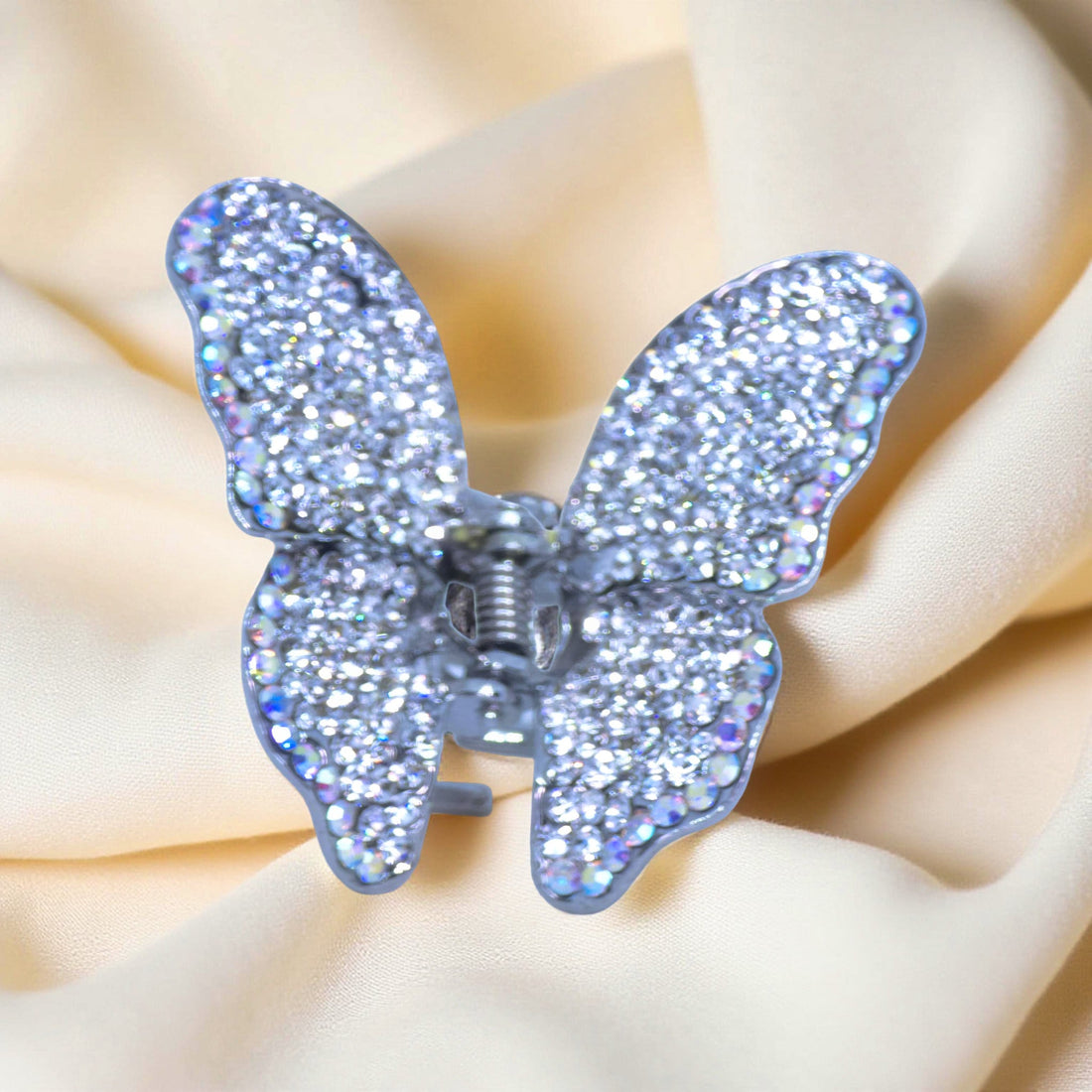 Haerime Papillora Mini Claw in Clear – top view of frosty clear crystal wings on neutral beige satin with subtle folds