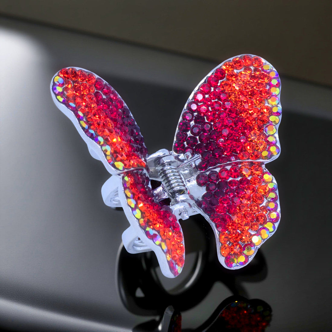 Haerime Papillora Mini Claw in Red – close-up of deep red pavé wings and arched spring clasp against soft neutral fabric