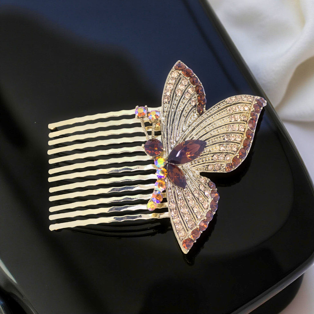 Haerime Papillora Twin Comb in Amber – honey-toned mirrored wing comb resting on folded cream satin fabric