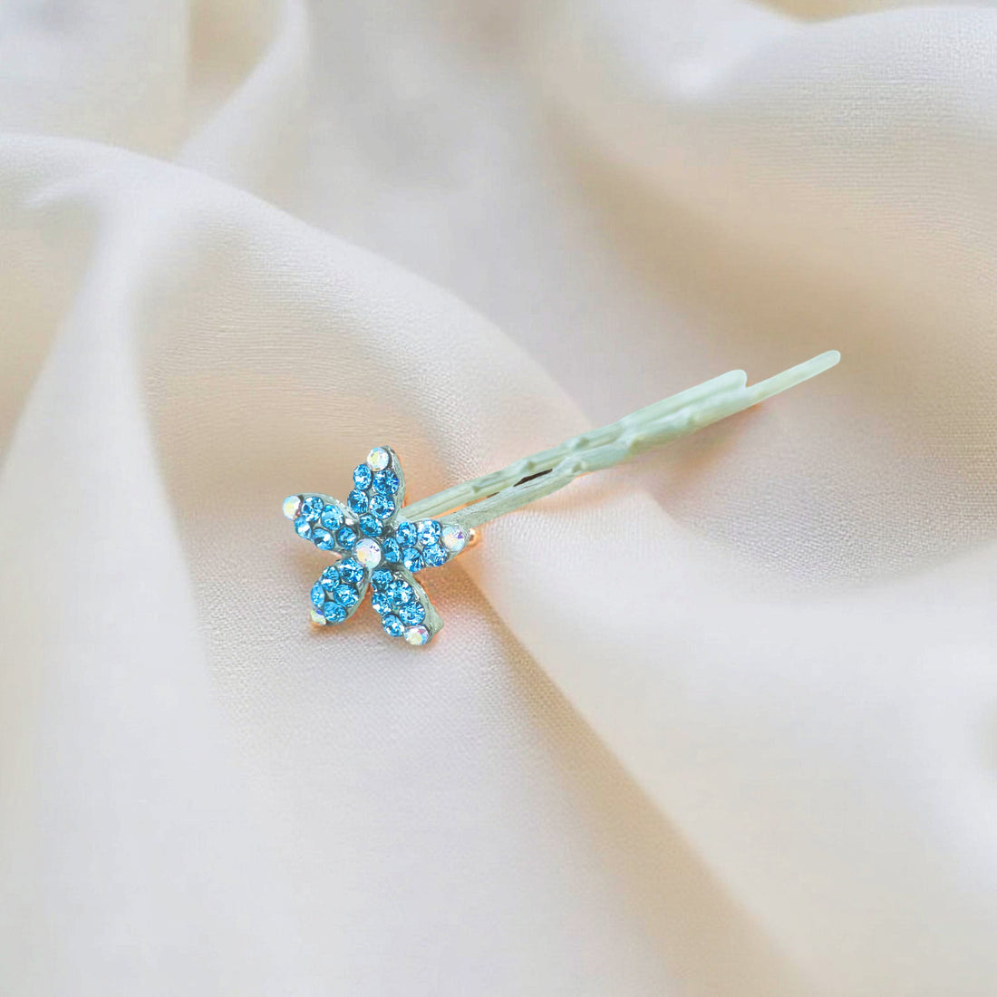 Haerime Petalight Hair Stick in Blue Zircon – top view of aquamarine crystal flower laid on wavy silver pin over velvet base