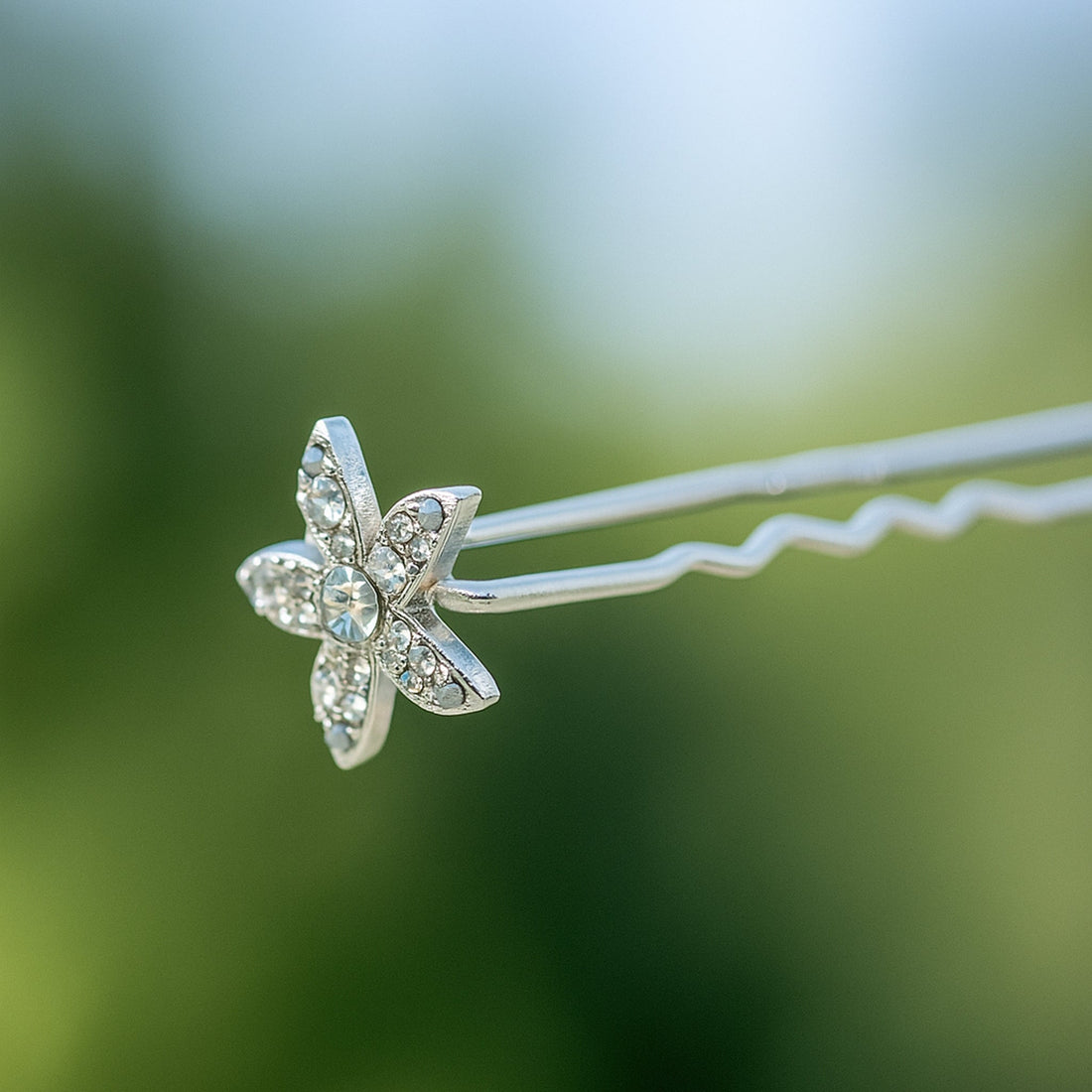 Haerime Petalight Hair Stick in Clear – close-up of frosted crystal blossom placed on pearlescent satin folds