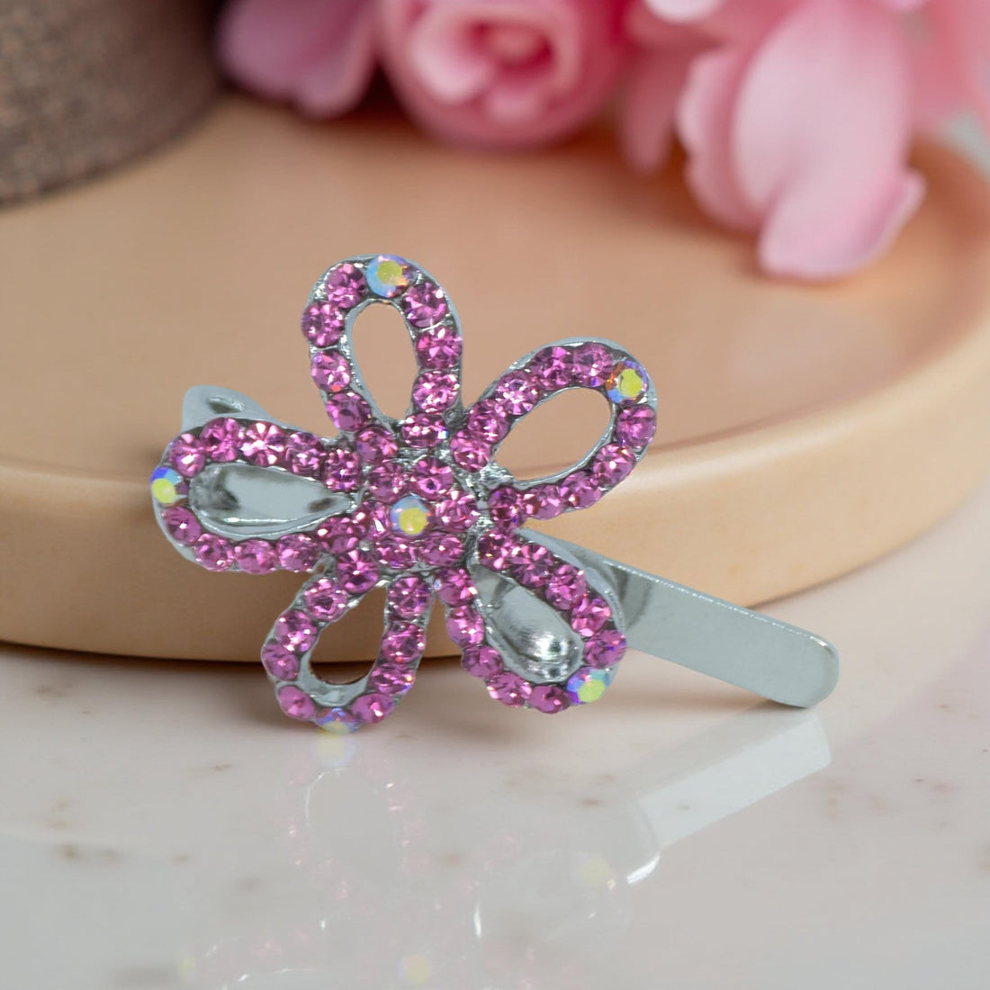 Haerime PetalMuse Magnetique in Pink – blush-toned crystal flower clip placed on pale silk pouch with reflected highlights