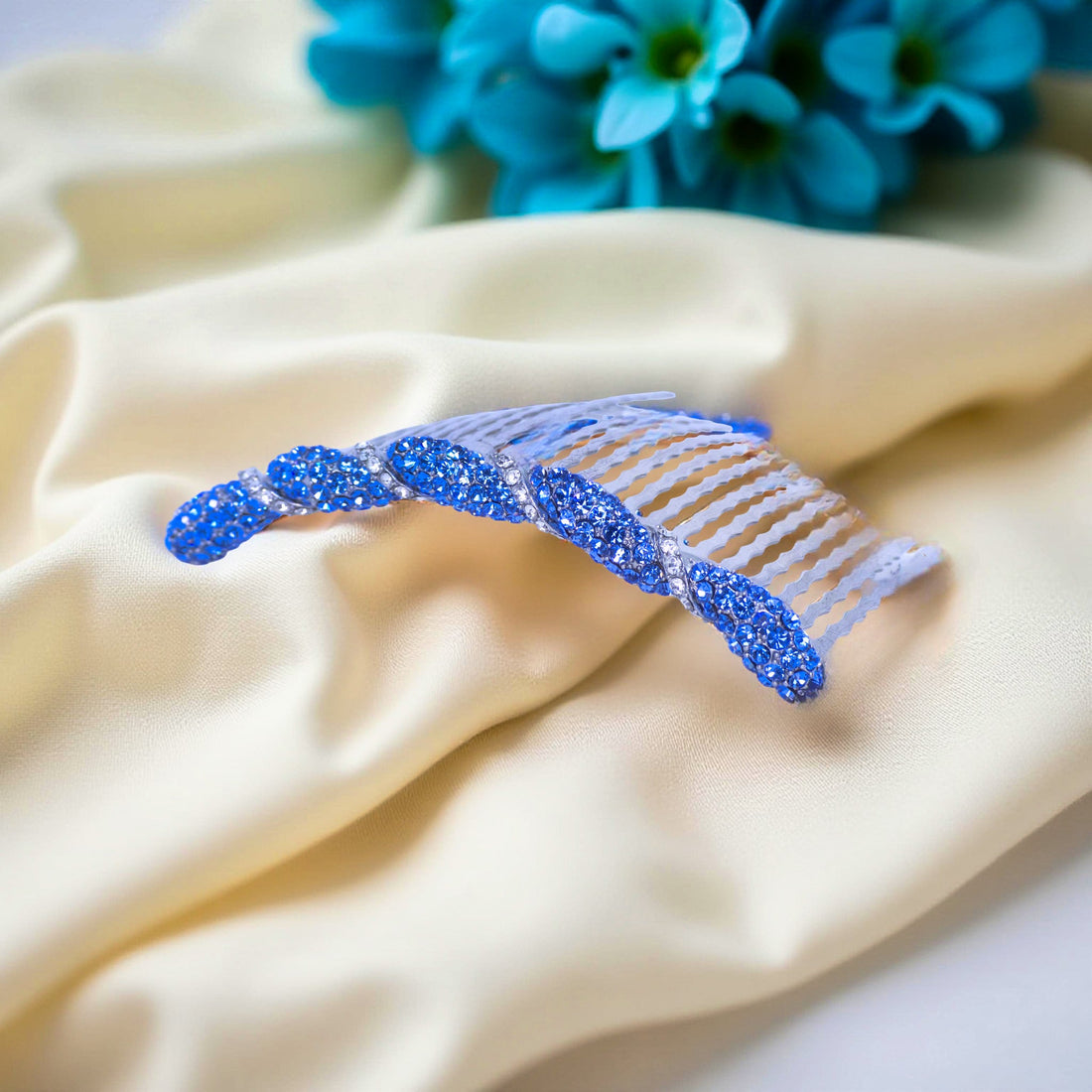 Haerime Seraphine Twist Comb in Blue – close-up of sapphire crystal bands resting on matte violet textile with soft light and petal accents