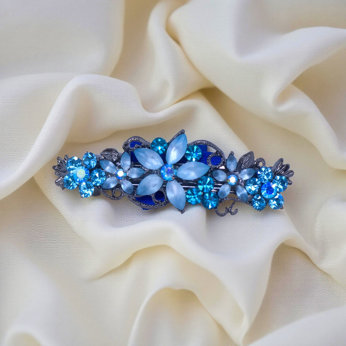 Haerime Serenbelle Bloom in Aquamarine – top view of sky blue crystal flower barrette placed on smooth satin pouch