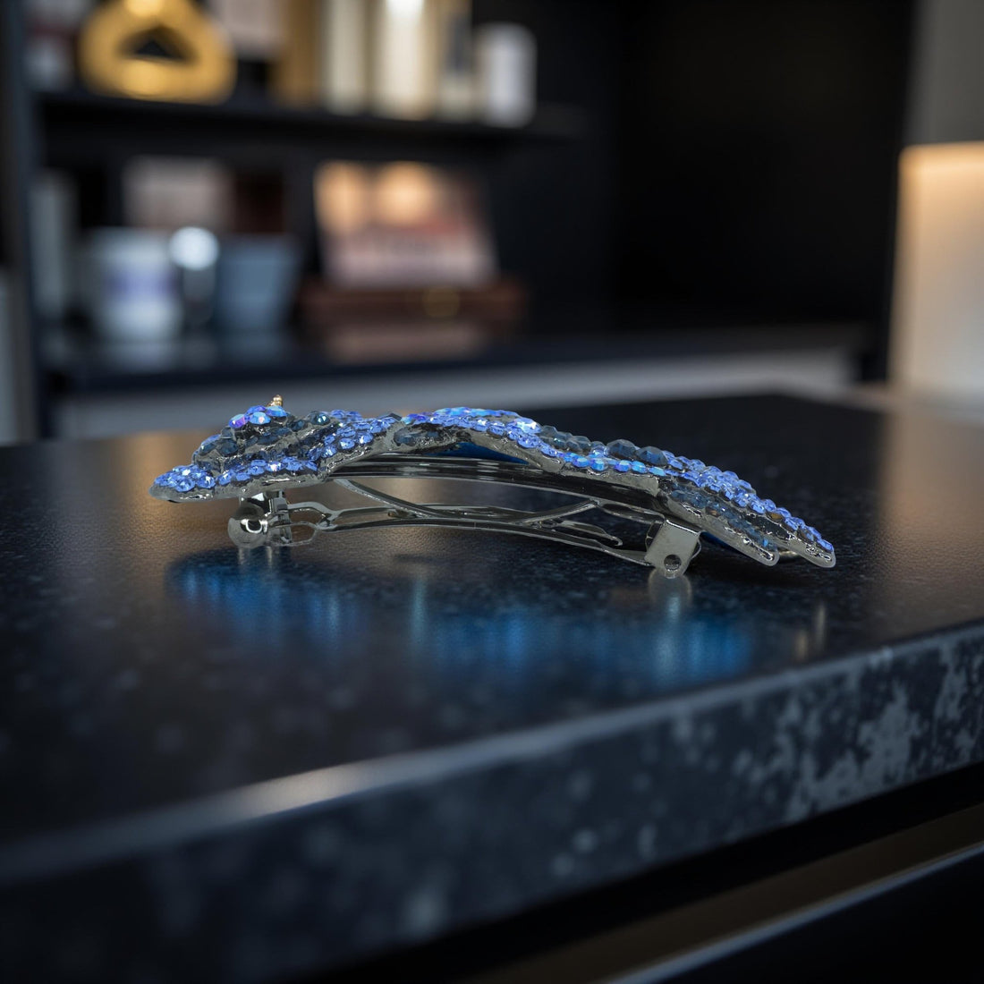 Haerime Twilight Bloom Mini in Blue – side angle showing arched crystal floral comb with French clasp, resting on matte stone tabletop in soft indoor light