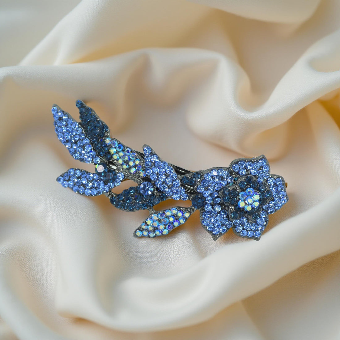 Haerime Twilight Bloom Mini in Blue – top view of navy-toned crystal flower arc on peach velvet