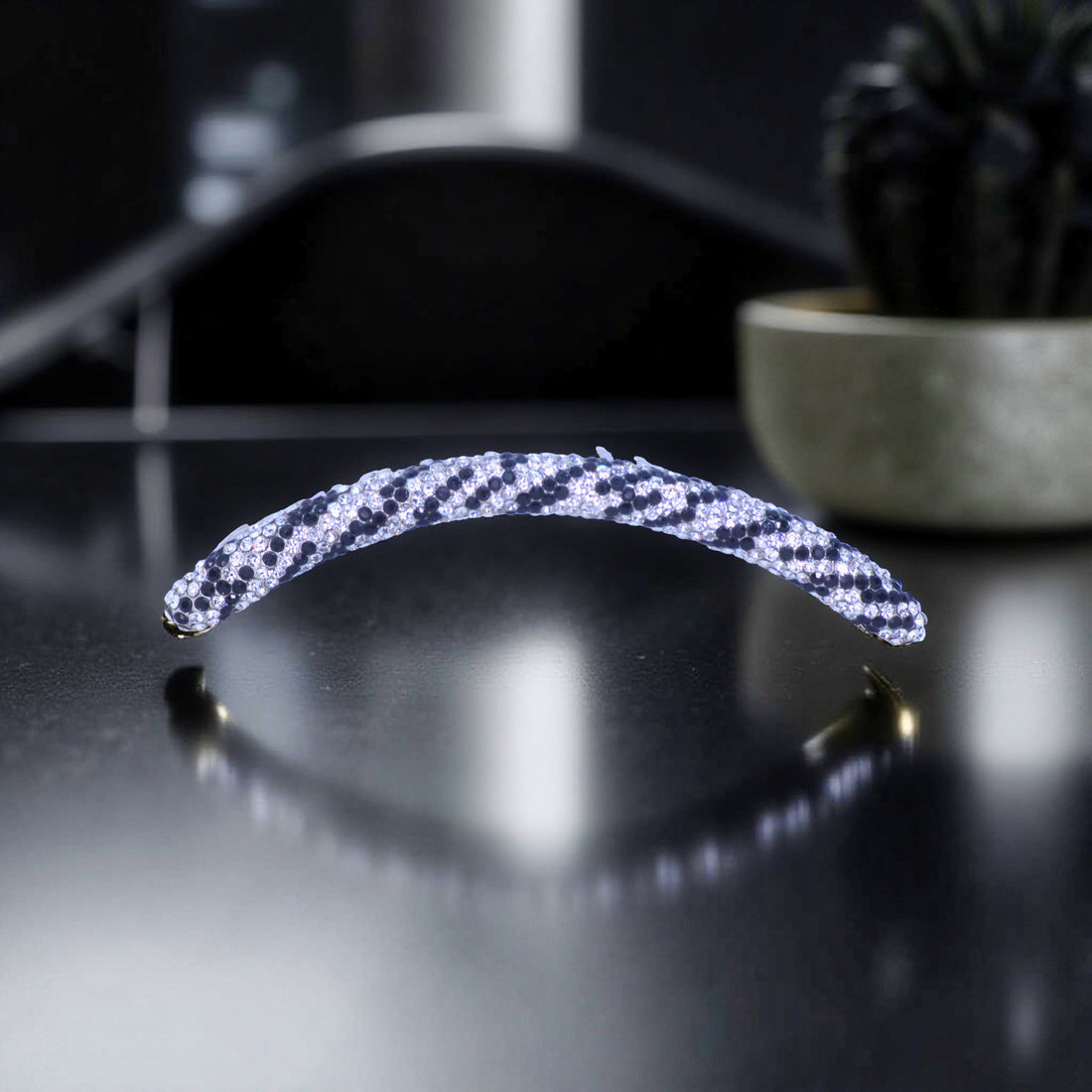 Haerime Velvette Arc in Ice Panther – long crystal arc comb with black and silver animal pattern resting on matte stone counter in studio light
