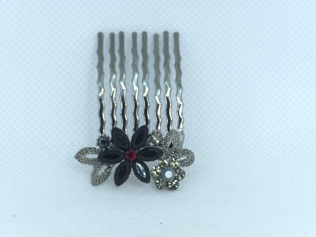 Florelle hair comb in Black, showing one complete comb with waved prongs and a flower-shaped decorative end on pale fabric.