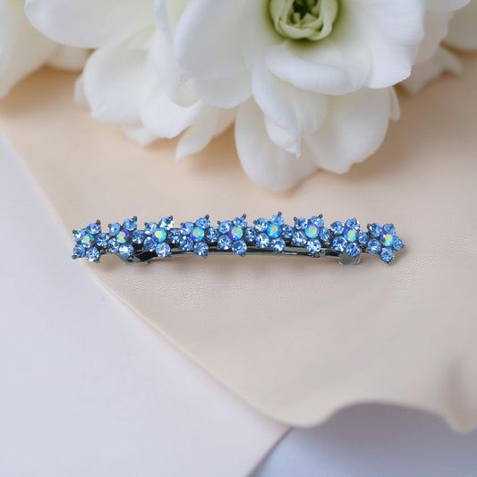 Haerime Aureflor Arc Barrette in Blue – arc-shaped barrette with oversized crystal flowers, styled on ivory satin with directional lighting