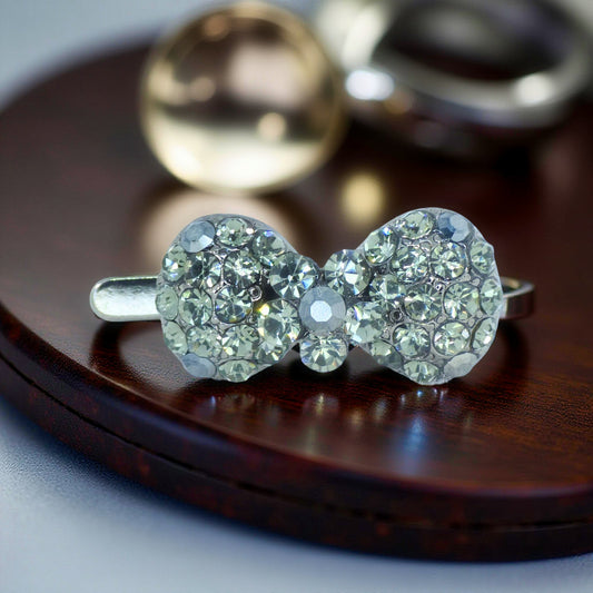 Haerime Chérie Clip in Black – mini Haerime Chérie Clip in Black – mini crystal bow barrette displayed on dark wood surface with glossy enamel shine