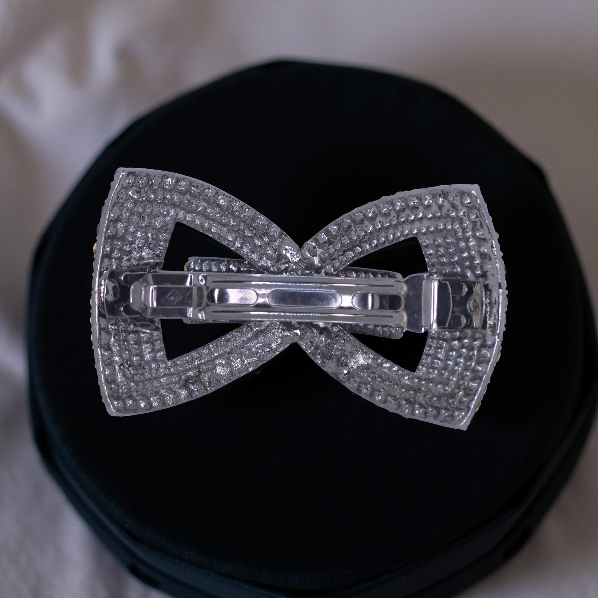 Back view of Haerime Ecliptique Bow Barrette in Red – reinforced spring clasp and contoured underframe against fabric background