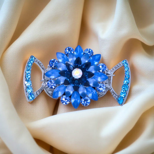 Haerime Floréa Blossom Claw in Blue – 3D crystal flower jaw clip displayed on soft ivory satin, layered petals with marquise stones