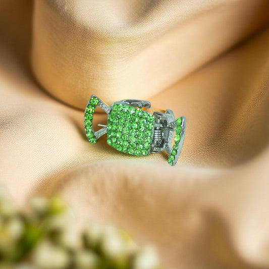 Haerime LumiClasp Mini in Peridot – front view of petite crystal jaw clip in light green, resting on soft gold satin
