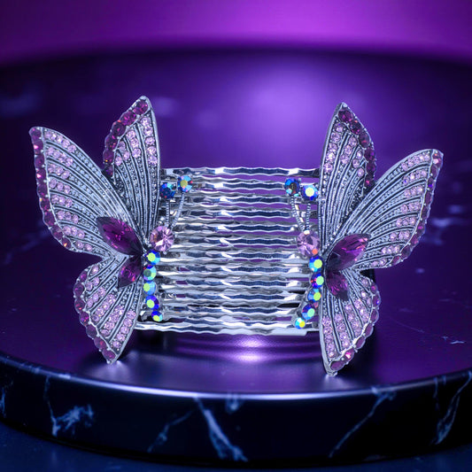 Haerime Papillora Twin Comb Set in Purple – mirrored butterfly hair combs with lavender pavé crystals, displayed on glossy plum-toned acrylic pedestal under dramatic lighting