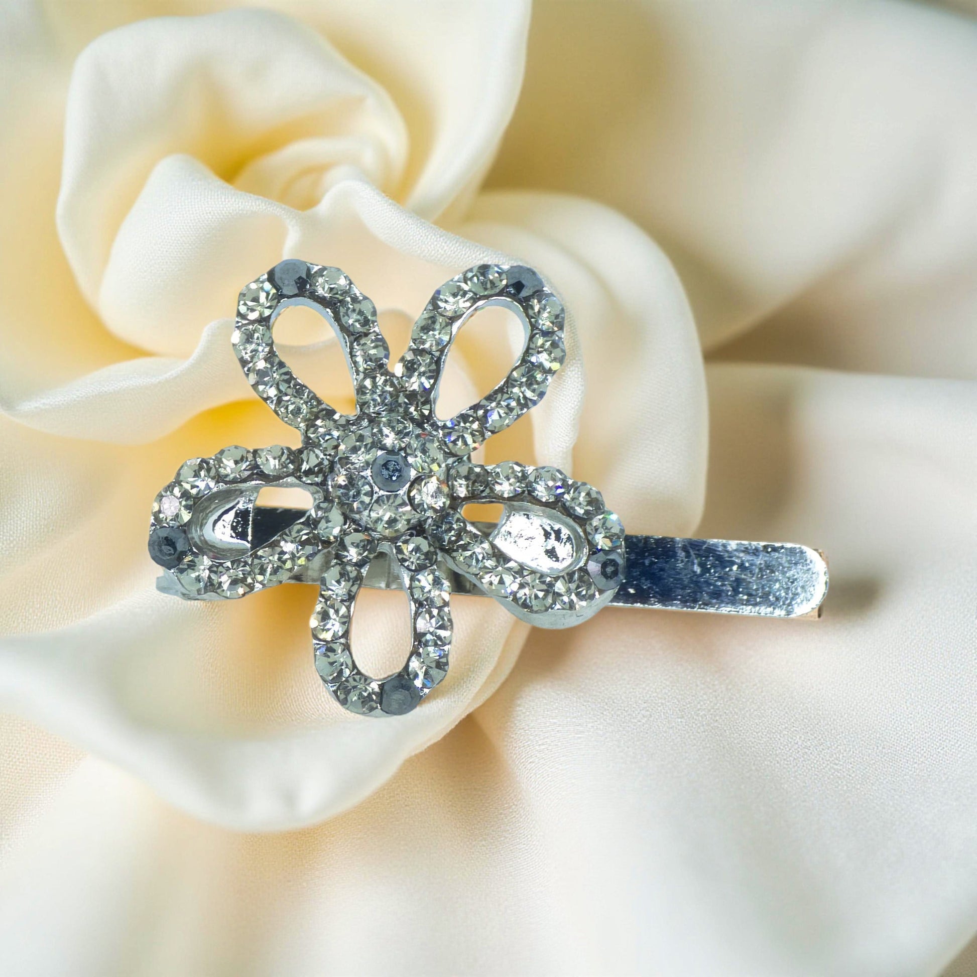 Haerime PetalMuse Magnetique in Black – jet crystal mini flower clip on cream satin with soft shadow transitions
