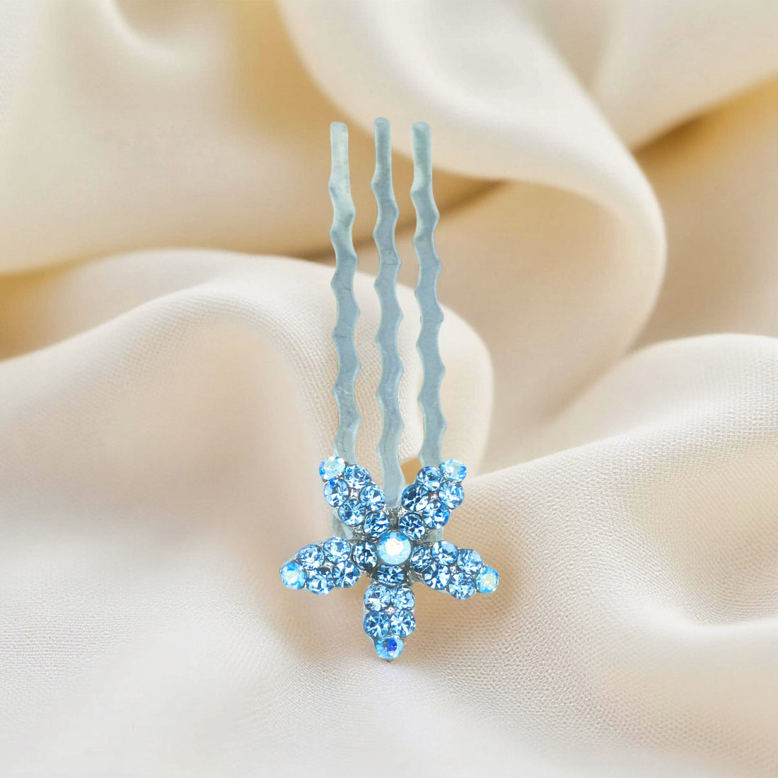 Haerime Starpetal Minis in Aquamarine – sky blue mini flower clip placed on pastel satin folds in soft natural light
