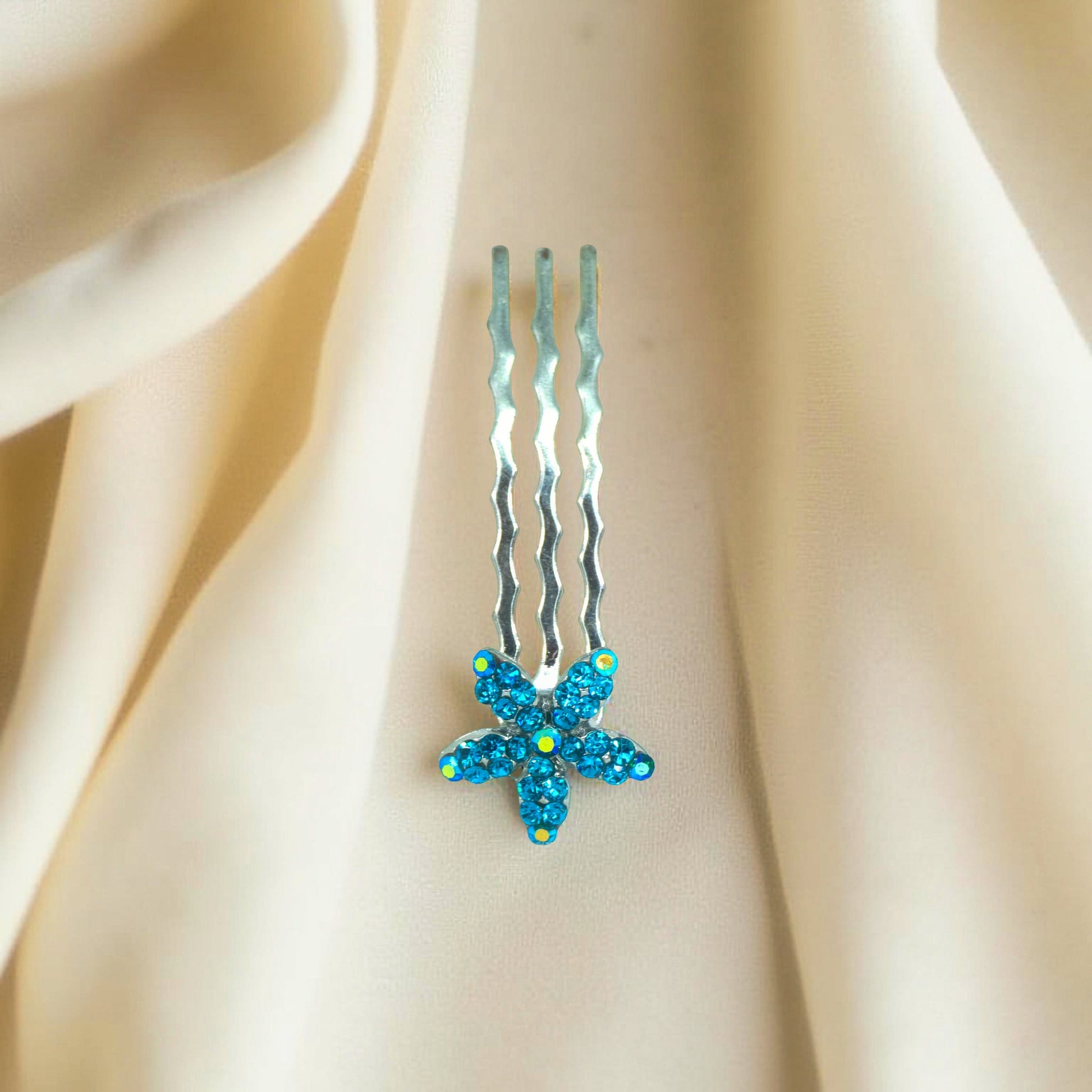 Haerime Starpetal Minis in Blue Zircon – top view of teal pavé five-petal pin resting on soft cream surface