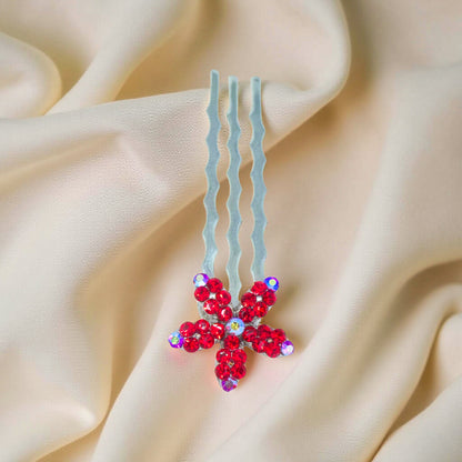 Starpetal Minis hair accessory in Red, with three waved prongs and a flower-shaped end, shown on pale fabric.