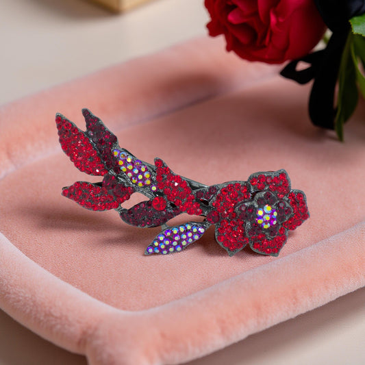 Haerime Twilight Bloom Mini in Red – ruby crystal floral barrette placed on peach velvet tray with red rose accent in warm natural light
